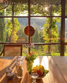 a wooden table topped with fruit on top of a wooden floor next to a window