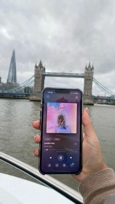 someone is holding up their cell phone to take a photo in front of the tower bridge