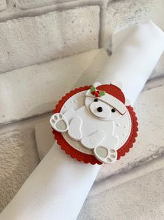 a white napkin with a red and white santa bear on it's face is sitting on top of a brick wall