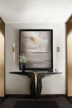 a black and gold console table with a vase on it in front of a painting