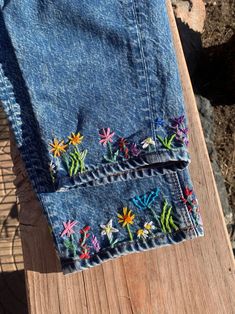 a pair of jeans with embroidered flowers on them