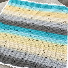 a crocheted blanket on top of a bed next to a pillow and pillows