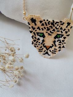 a beaded necklace with a leopard head on it next to some dried flowers and a gold chain