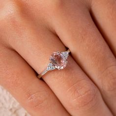 a woman's hand with a pink diamond ring on top of her left hand