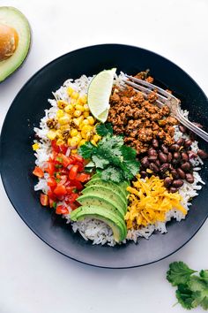 a plate filled with rice, beans, avocado and other foods