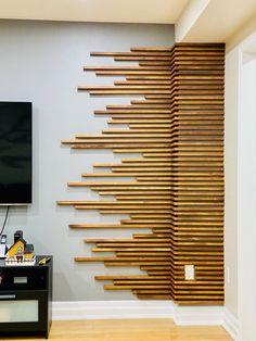 a flat screen tv mounted to the side of a wall next to a wooden slatted design