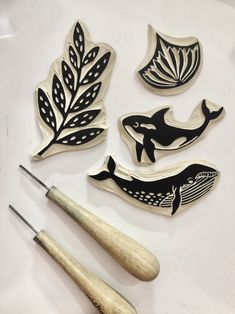 some wood carving tools sitting on top of a white table next to leaves and a whale