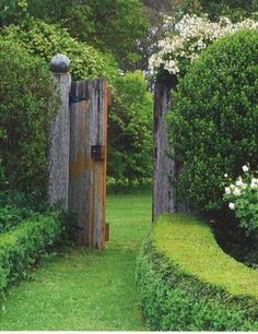 a wooden gate in the middle of a lush green garden