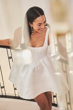 a woman in a white dress is walking down the stairs