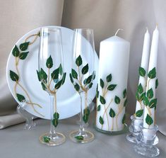 a white plate topped with three glasses and two candles next to each other on top of a table