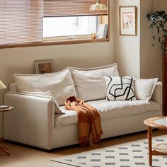 a living room with a white couch and wooden table in front of the window,