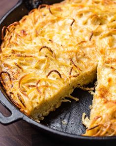 a cheesy dish is shown in a cast iron skillet on a wooden table