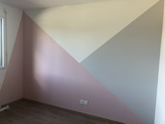 an empty room with pink and grey paint on the wall next to a large window