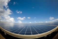 an array of solar panels under a partly cloudy blue sky