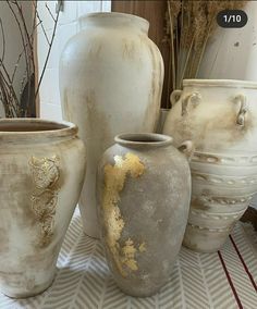 several vases with gold paint on them are sitting on a table next to each other