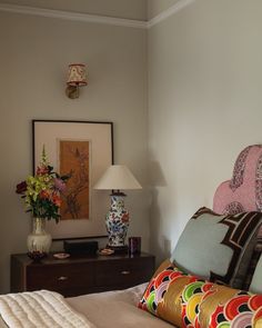 a bed with colorful pillows and a lamp on top of the headboard in a bedroom