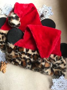 a stuffed animal is laying on top of a leopard print blanket and some snowflakes