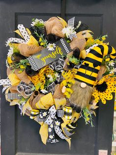 a yellow and black wreath on the front door with a bee decoration hanging from it's side