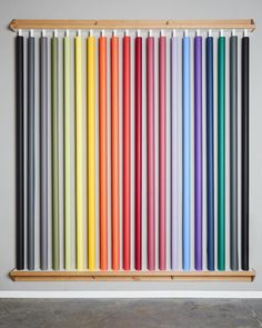 a wooden shelf with many different colored pencils on the wall and in front of it