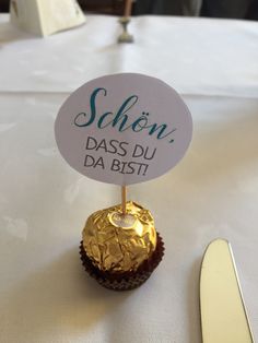 a table topped with a cupcake and a sign that says schon pass du da bist