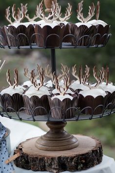 there are cupcakes that have been placed on a cake stand with antlers