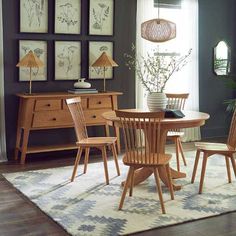 a dining room table with chairs and pictures on the wall above it, along with an area rug