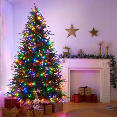 a brightly lit christmas tree in a living room with presents on the floor next to it