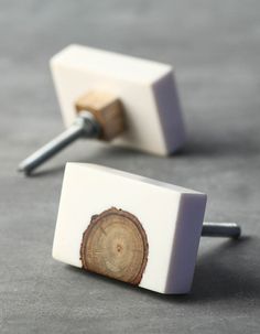 two white square wooden cufflinks with a tree stump in the center on a gray surface