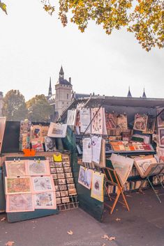 an outdoor flea market with lots of art and books on the tables in front of it