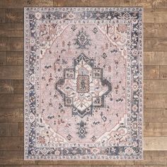 a pink rug with an ornate design on the floor in front of a wooden wall