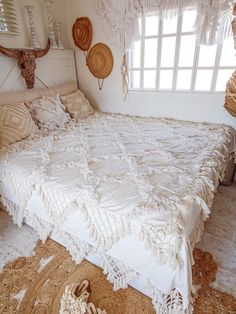 the bed is made up with white linens and fringed bedspreads on it