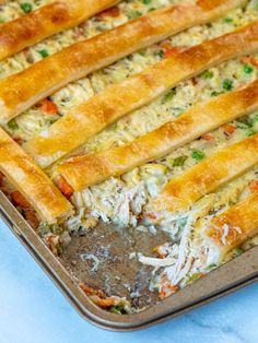 a casserole dish with chicken, cheese and vegetables in it on a blue table cloth