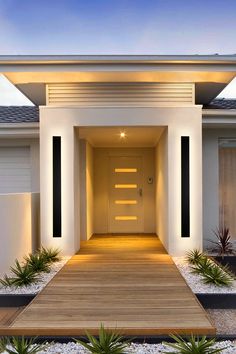 the entrance to a modern house with wooden steps leading up to it's front door