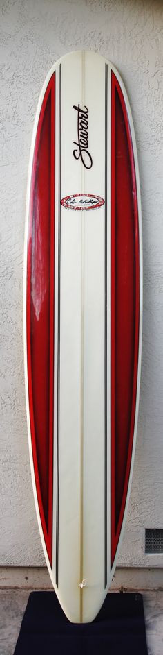 a red and white surfboard leaning up against a wall