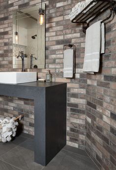 a bathroom with brick walls and a sink in the middle, along with a towel rack on the wall