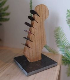 a wooden sculpture with several knives sticking out of it's back end on top of a table