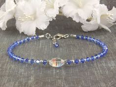 "The sparkling handmade 'Atlantis' is your 'Something Blue' sapphire wedding beaded anklet. Brides have been wearing something blue for centuries as it is tied to Old English \"Something old, something new, something borrowed, something blue.\" This is the perfect gift for her wedding day. This beaded anklet was designed with blue Swarovski crystal, tiny cream Charlotte glistening seed beads, Bali 925 silver and finished with a marine dolphin lobster clasp. Available in light sapphire, sapphire Blue Beaded Bracelets For Weddings, Blue Round Bead Bracelets For Weddings, Blue Round Beads Bracelet For Wedding, Adjustable Blue Beaded Bracelets For Wedding, Adjustable Blue Bracelets For Anniversary, Blue Faceted Beads Jewelry For Wedding, Adjustable Sapphire Bracelets For Wedding, Adjustable Blue Crystal Bracelet For Anniversary, Blue Round Beads Anklets For Gifts