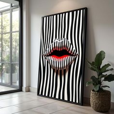 an art piece with a woman's mouth and tongue painted on the wall next to a potted plant