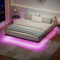 a large bed sitting in the middle of a room with pink lights on it's sides