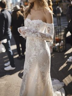 a woman in a wedding dress is standing on the street