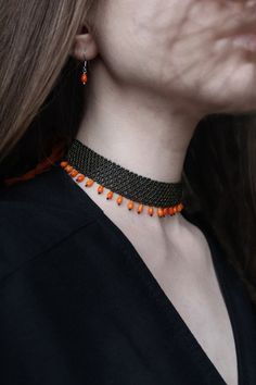 a woman wearing an orange and black beaded choker