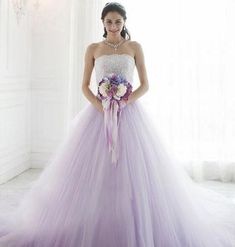 a woman in a purple and white wedding dress holding a bouquet with her hands on her hips