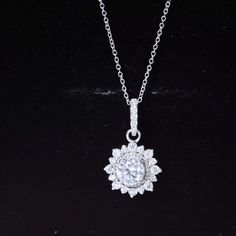 a white diamond necklace on a black surface with a chain attached to the back of it