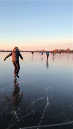 people skating on an ice covered lake at sunset or dawn with the sun setting in the background