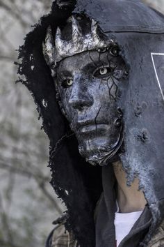 a person wearing a black and white mask on top of their head with trees in the background