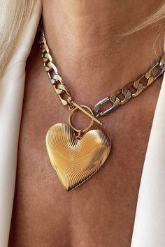 An oversized gold heart pendant hangs from a bold statement figaro link chain with a toggle clasp closure! Chunky Necklace Gold, Chunky Metal Necklace With Heart Pendant, Chunky Heart Pendant Jewelry Gift, Chunky Metal Heart Pendant Necklace, Metal Heart Necklace With Chunky Chain, Chunky Heart Pendant Necklace As Gift, Gold Chunky Heart-shaped Jewelry, Chunky Heart Pendant Necklace For Valentine's Day, Gold Chunky Chain Necklace For Valentine's Day