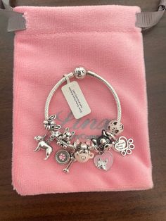 a bracelet with charms on it sitting in a pink bag