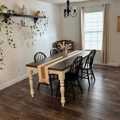 a dining room table with four chairs and a potted plant on the wall above it