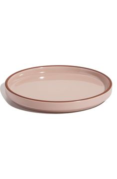 a pink and brown plate on a white background with the rim slightly tilted to the side