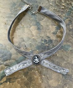 This is my version of the family crest choker as seen worn by the amber eyed vampire family. The crest is set behind glass into an antiqued silver bezel. Its attached to a 14 inch choker with an adjustable clasp. The choker is made of cotton and lace, carefully stitched together to give it a unique antique shabby chic feel. This makes an excellent gift for a loved one or yourself. Victorian Silver Costume Jewelry, Handmade Silver Gothic Choker, Silver Vampire Choker For Halloween, Silver Vampire Costume Jewelry, Silver Vampire Style Costume Jewelry, Victorian Silver Choker, Medieval Jewelry For Halloween Gift, Victorian Silver Choker Necklace, Vintage Halloween Costume Necklaces